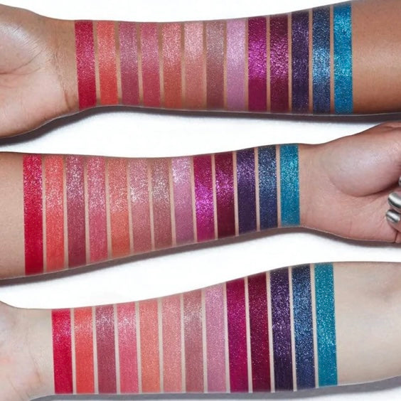 Model is showcasing her forearm with the entire Ciate glitter flip liquid lipstick collection in every color to show how the color would look on a white skin, Black and olive skin complexions