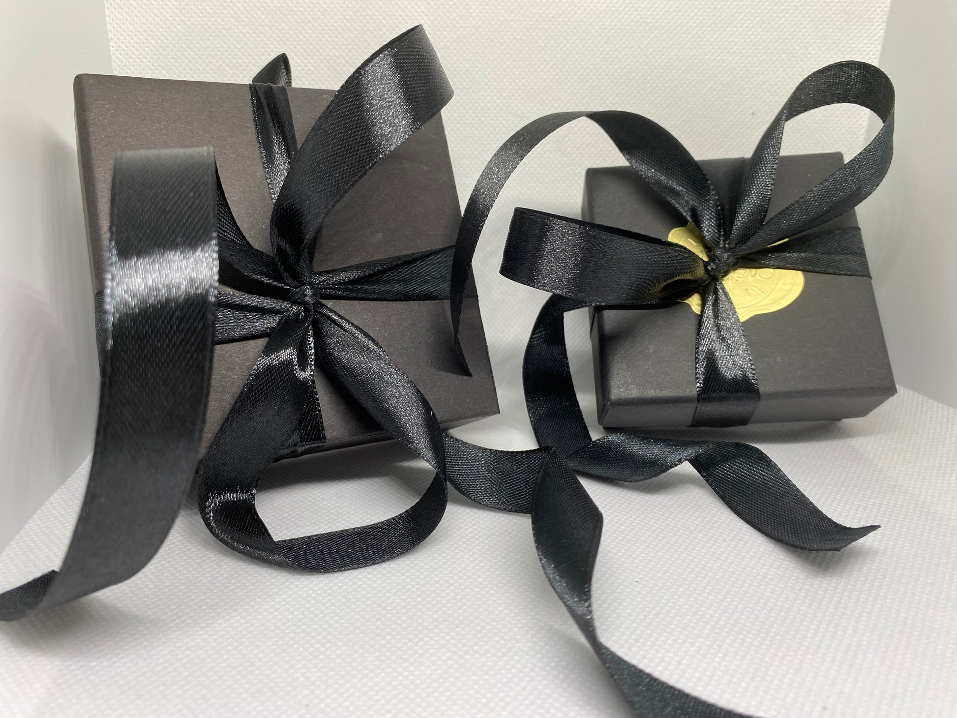 Beautiful black gift boxes with silky black ribbon tied in a bow with a gold raised sticker with logo. The gift box w/ matching ribbon is a free option if requested in the cart note during checkout.