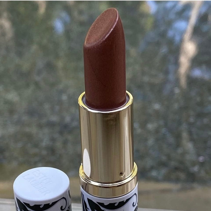 Estée Lauder Pure color Envy Limited Edition Lip sculpting lipstick in the color #111 Tiger Eye, lipstick is shown in a gold,  chrome case inside and on the outside the lipstick is in a blue and white case