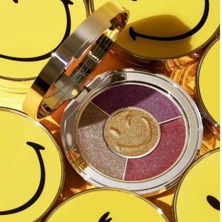 Ciate London smiley face eyeshadow compact with mirror showing the 4 colors of eyeshadow surrounded by several other smiley face compacts