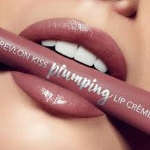Woman holding a Revlon's Kiss Plumping Lip Crème in shades #540 Velvet Mink in her mouth between her teeth smiling